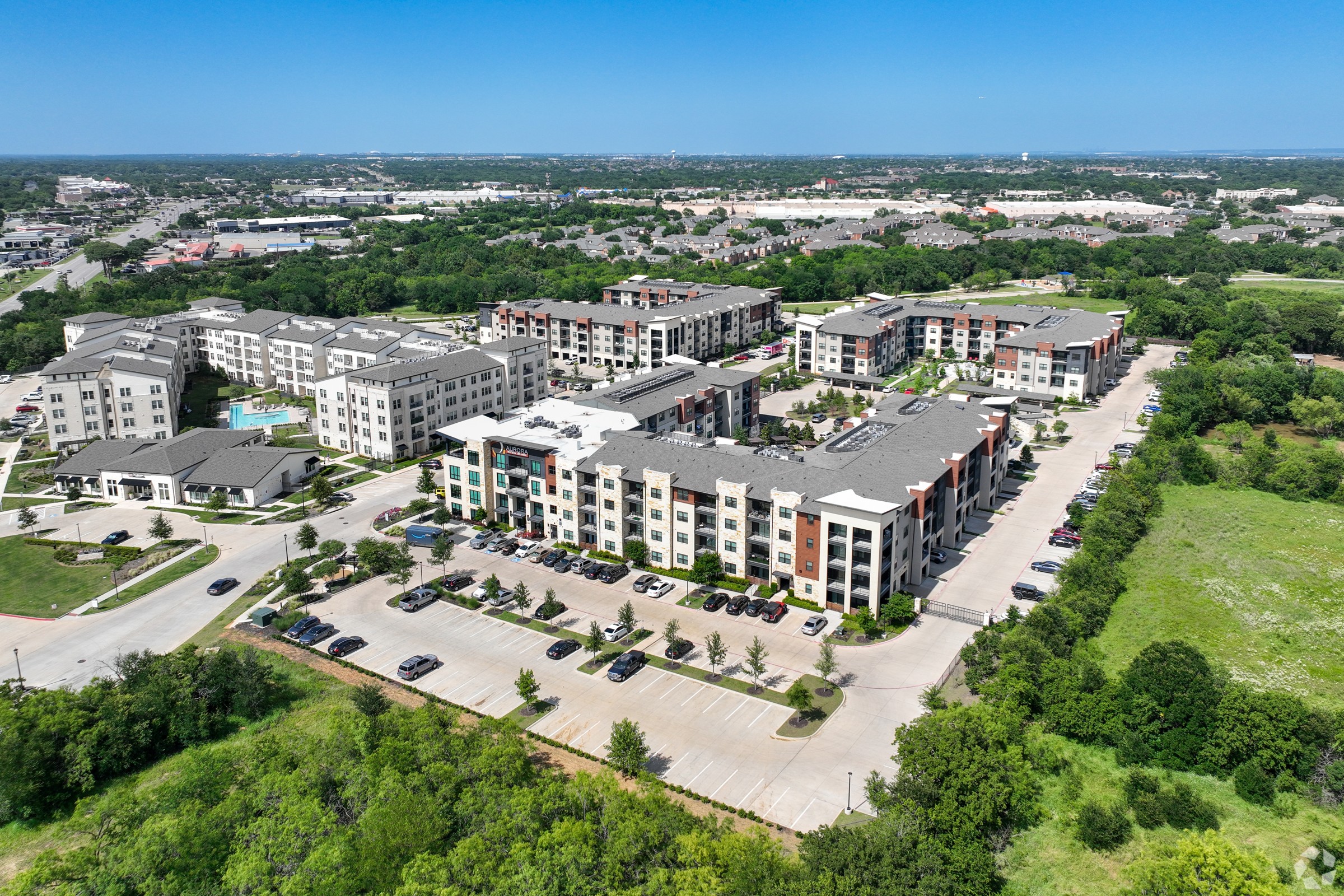 A bird's eye view of a large apartment complex surrounded by greenery and roads