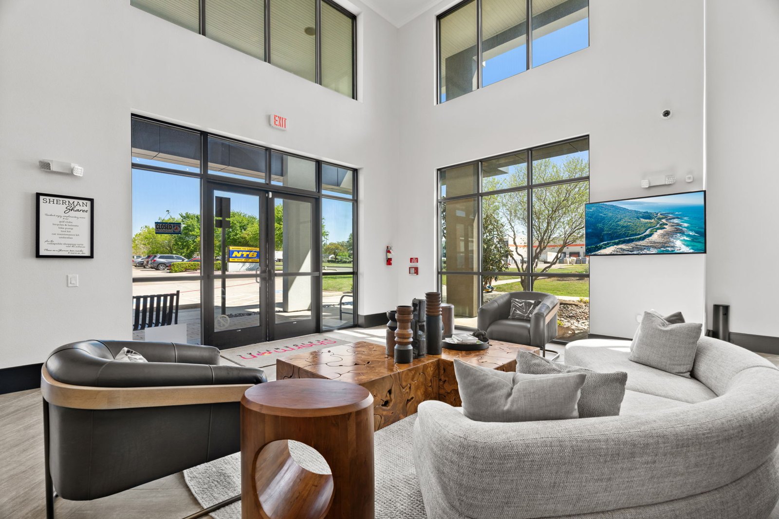 A living room with a grey couch and a black leather chair. at Axis at Watters Creek