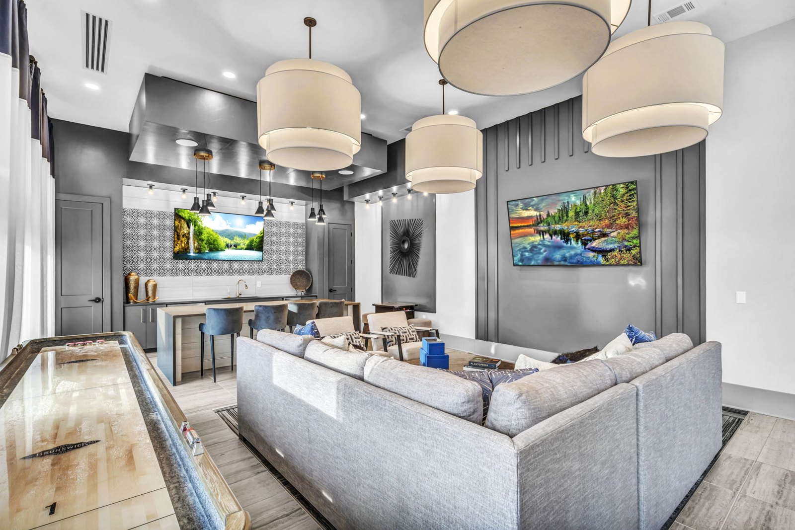 A modern living room with a grey couch and a pool table. at Axis Grand Crossing