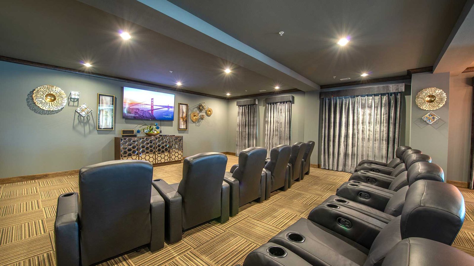 Two rows of luxury movie theater seats sit before a large screen on the left. at Bell Tower Reserve