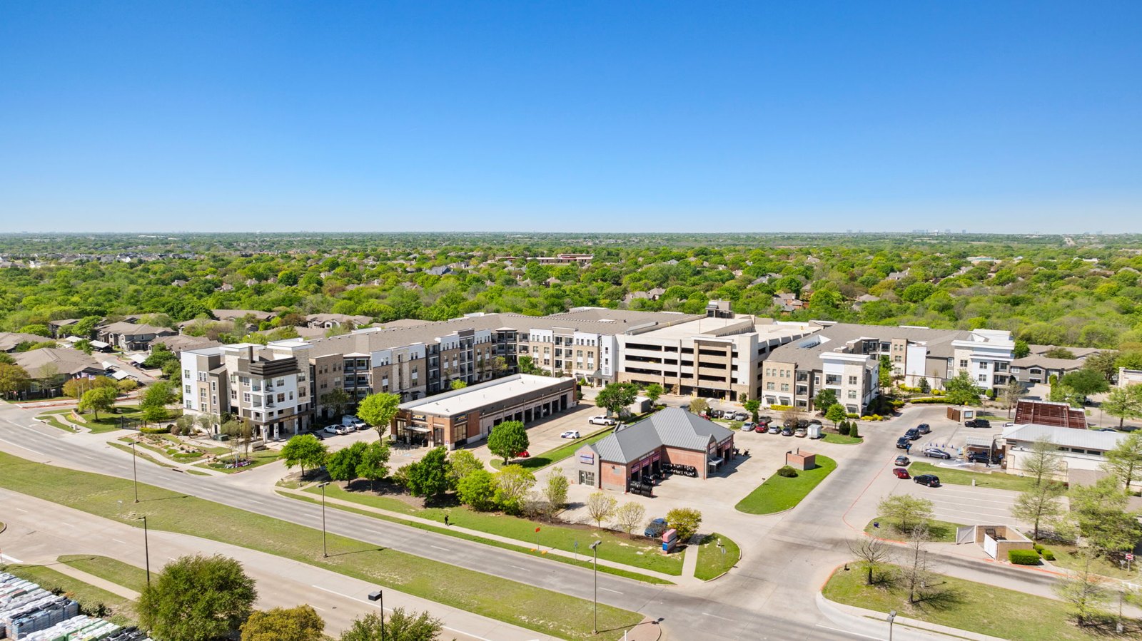 A view of a residential area with apartment buildings and a parking lot. at Axis at Watters Creek