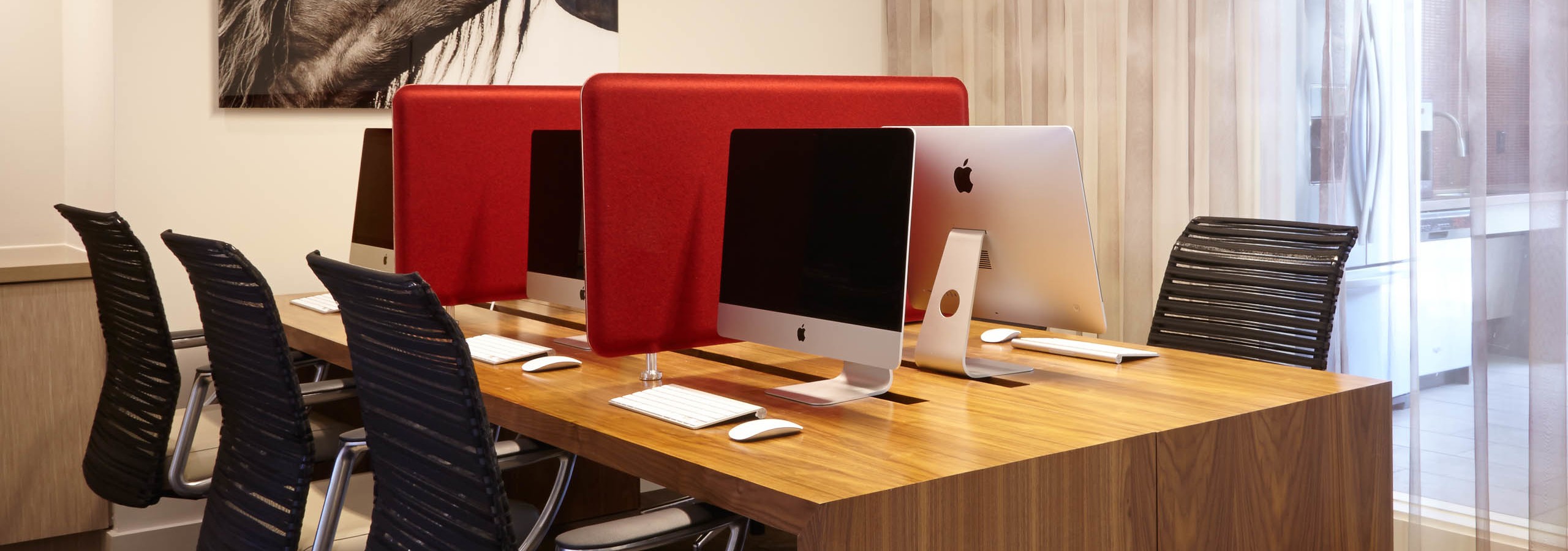 AMLI on Riverside business center with long wooden desk with black office chairs and Apple computers with bold red separators