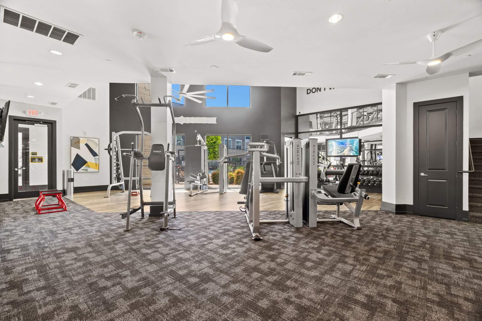 A gym with a variety of equipment including treadmills, weights, and a squ at Axis at Watters Creek