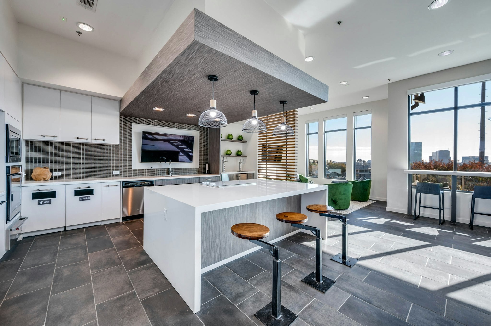 AMLI Frisco Crossing - Interior view of AMLI Frisco Crossing apartment sky lounge kitchen with island, pendant lights, bolted barstools, and stainless appliances
