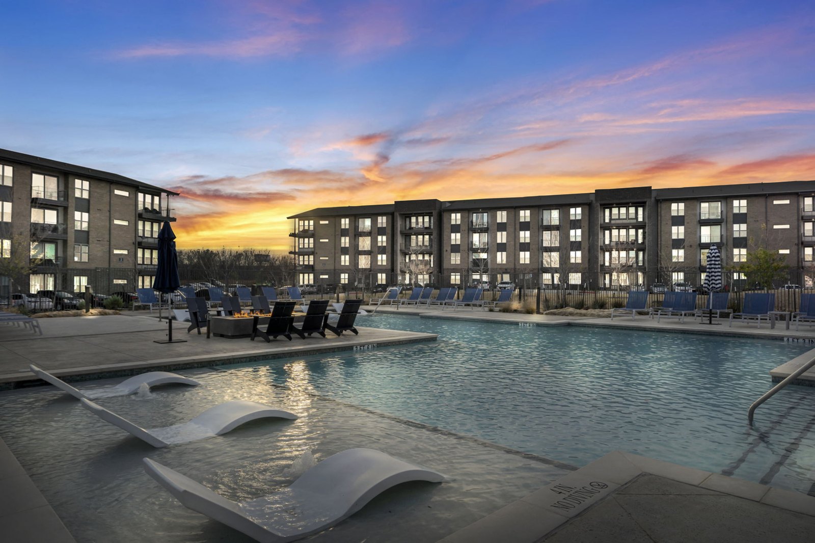 A modern pool area with a large rectangular pool and a smaller wavy pool next to it. at Axis Grand Crossing