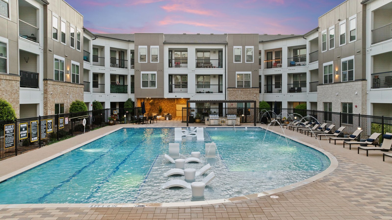 A large swimming pool in the middle of a courtyard surrounded by apartment buildings. at Axis at Watters Creek