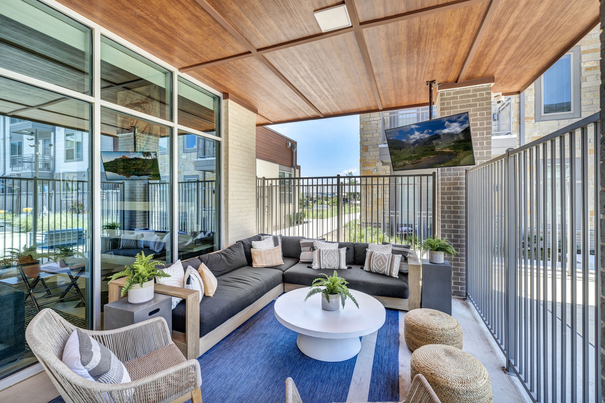 26 at City Point - A modern balcony with a sofa, chairs, and a TV