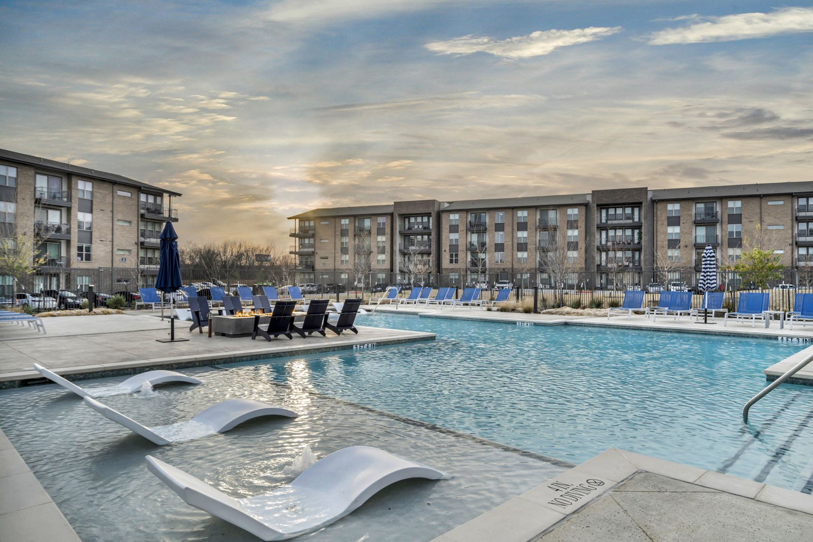 A swimming pool with a slide and loungers in front of apartment buildings. at Axis Grand Crossing