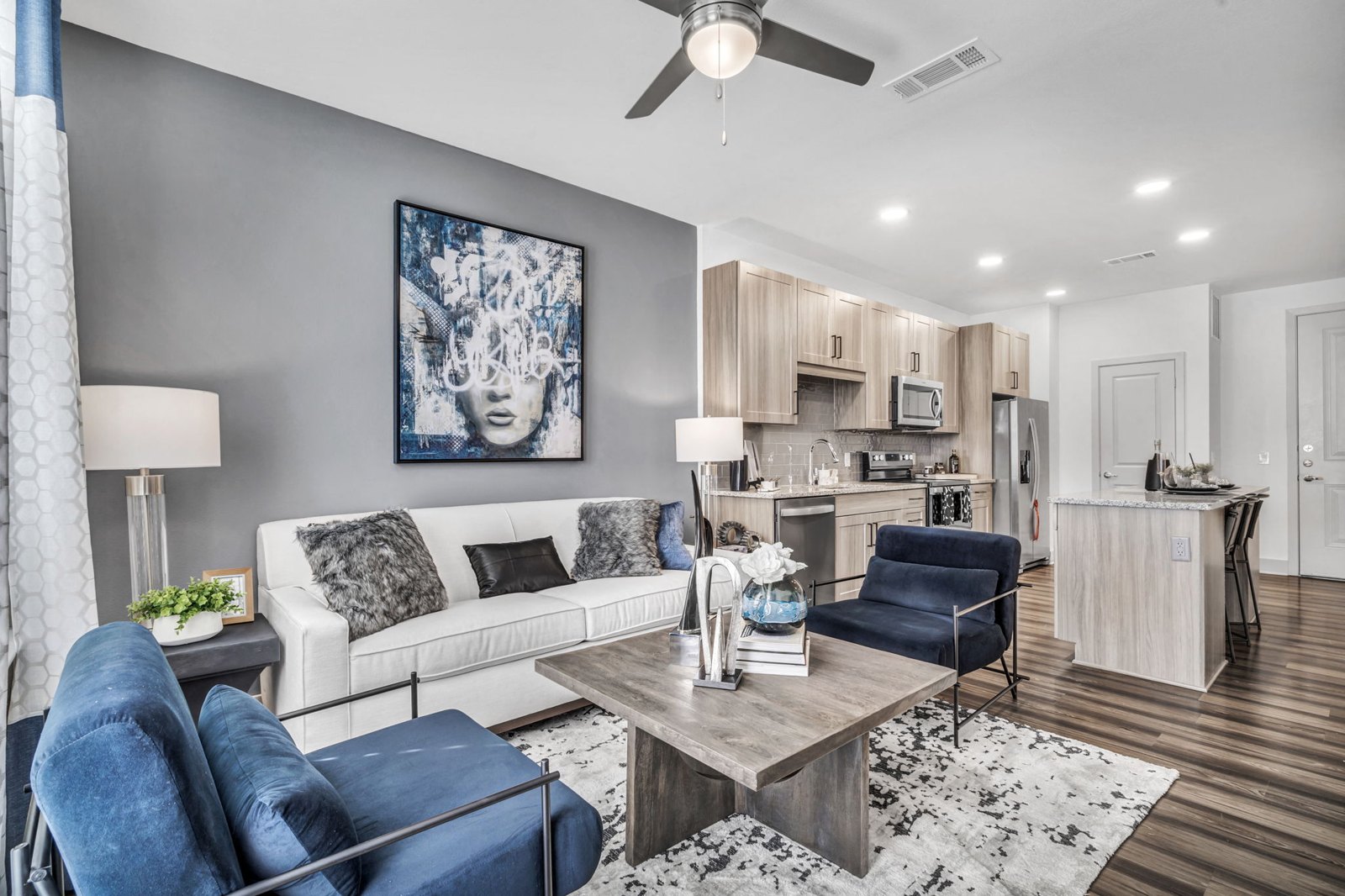A modern living room with a white couch, a coffee table, and a painting on the wall. at Axis Grand Crossing