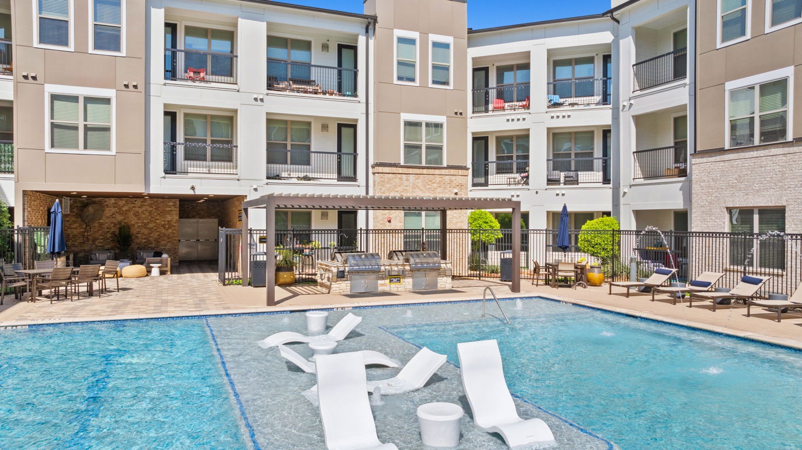 A swimming pool in front of apartment buildings. at Axis at Watters Creek