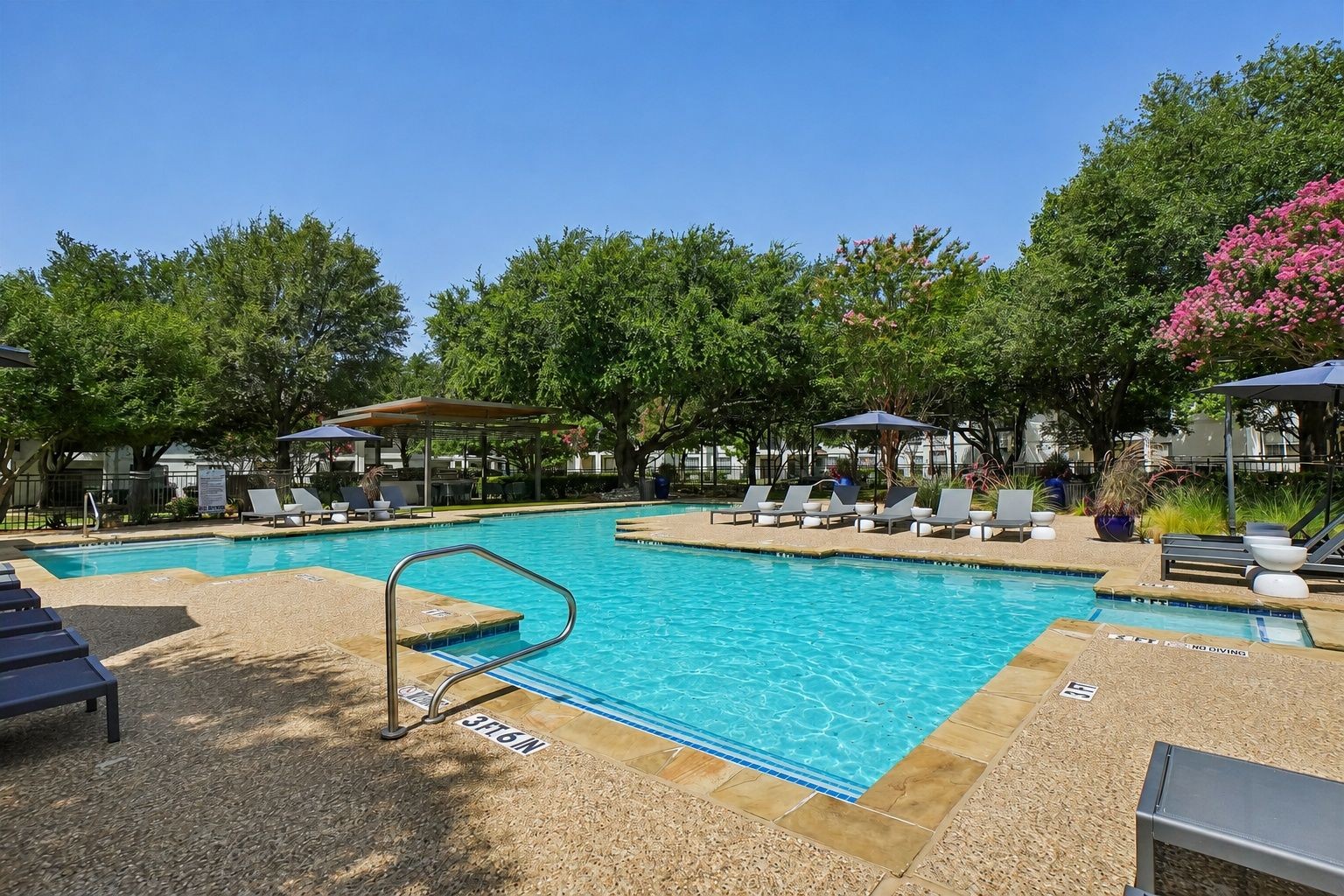 23Hundred at Ridgeview - A sparkling pool surrounded by lounge chairs and shaded areas, set against a clear blue sky