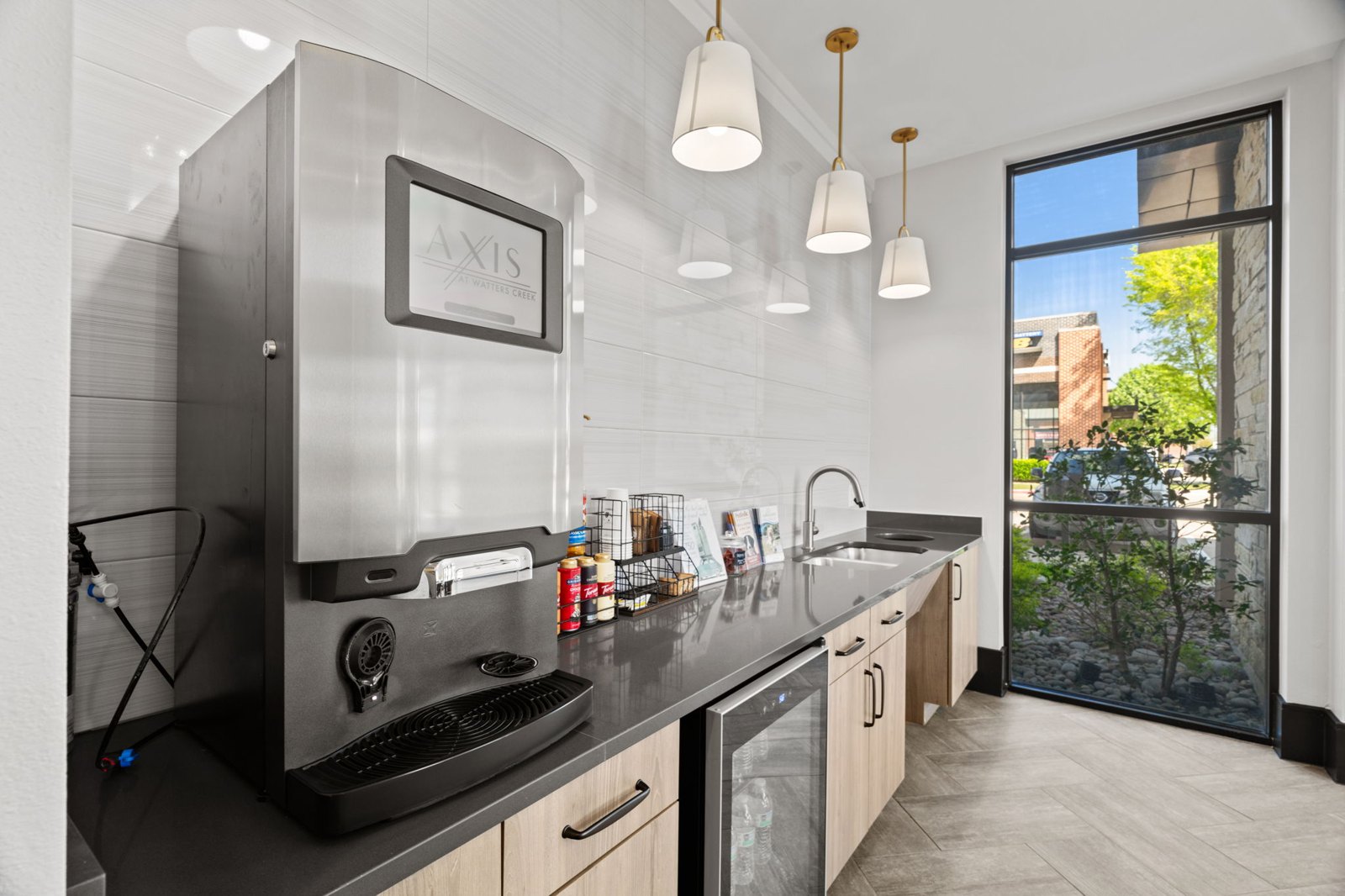 A modern kitchen with a large window overlooking a tree. at Axis at Watters Creek