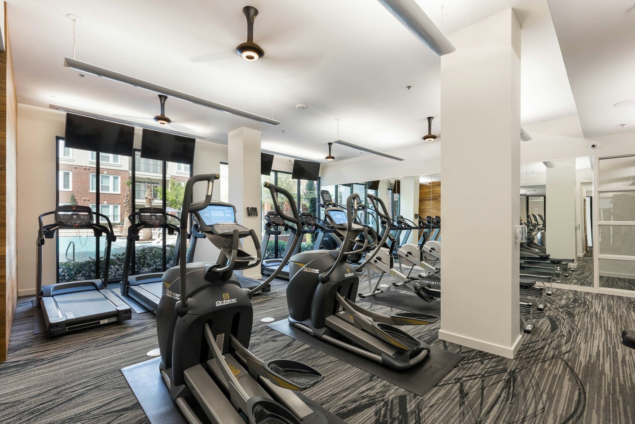 AMLI Frisco Crossing - AMLI Frisco Crossing fitness center with treadmills and other cardio machines and mounted TVs and ceiling fans above