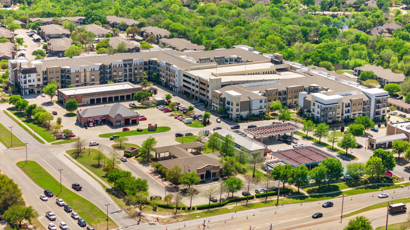 A large apartment complex with a parking lot in front. at Axis at Watters Creek