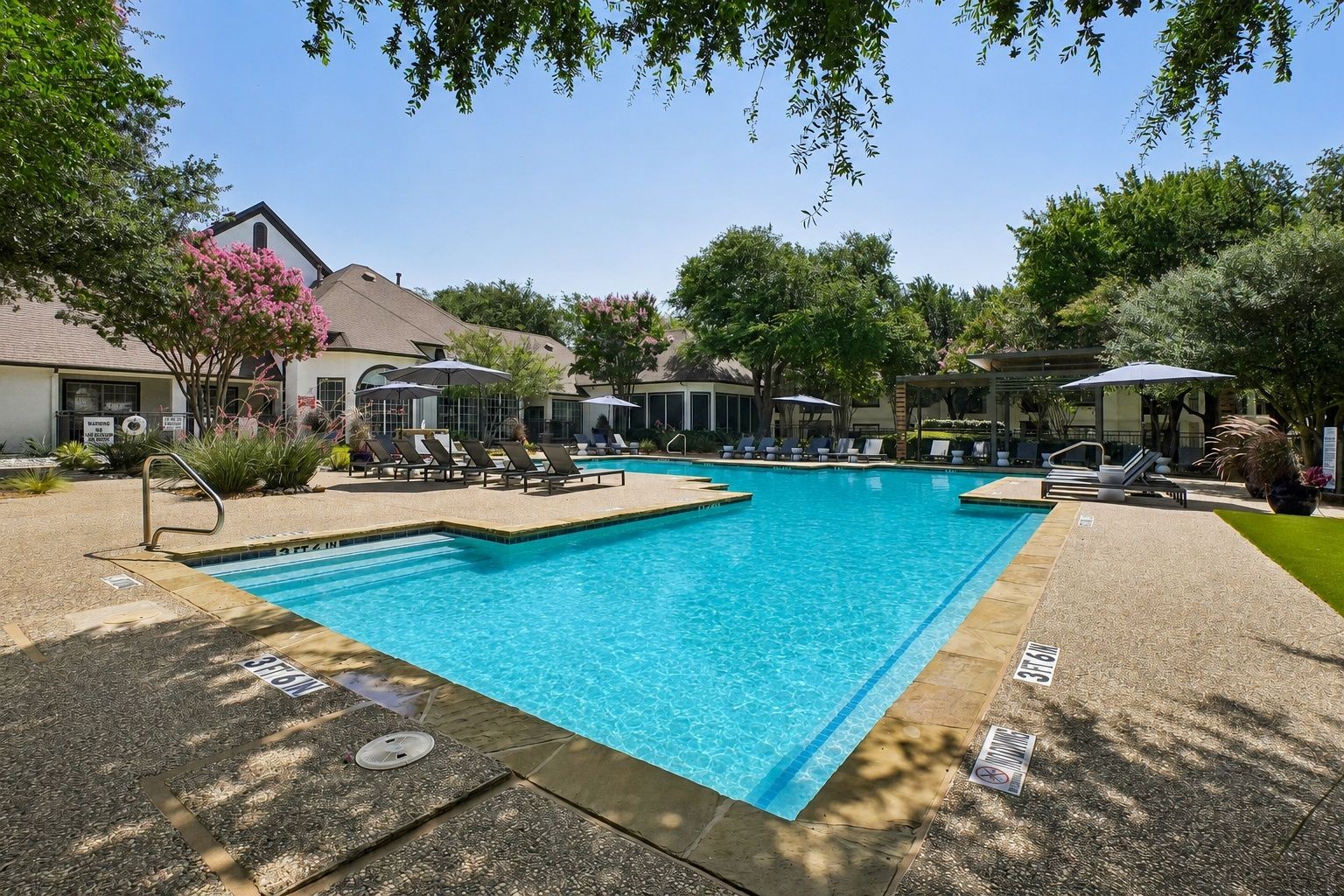 23Hundred at Ridgeview - A sunny poolside scene with lounge chairs and lush greenery