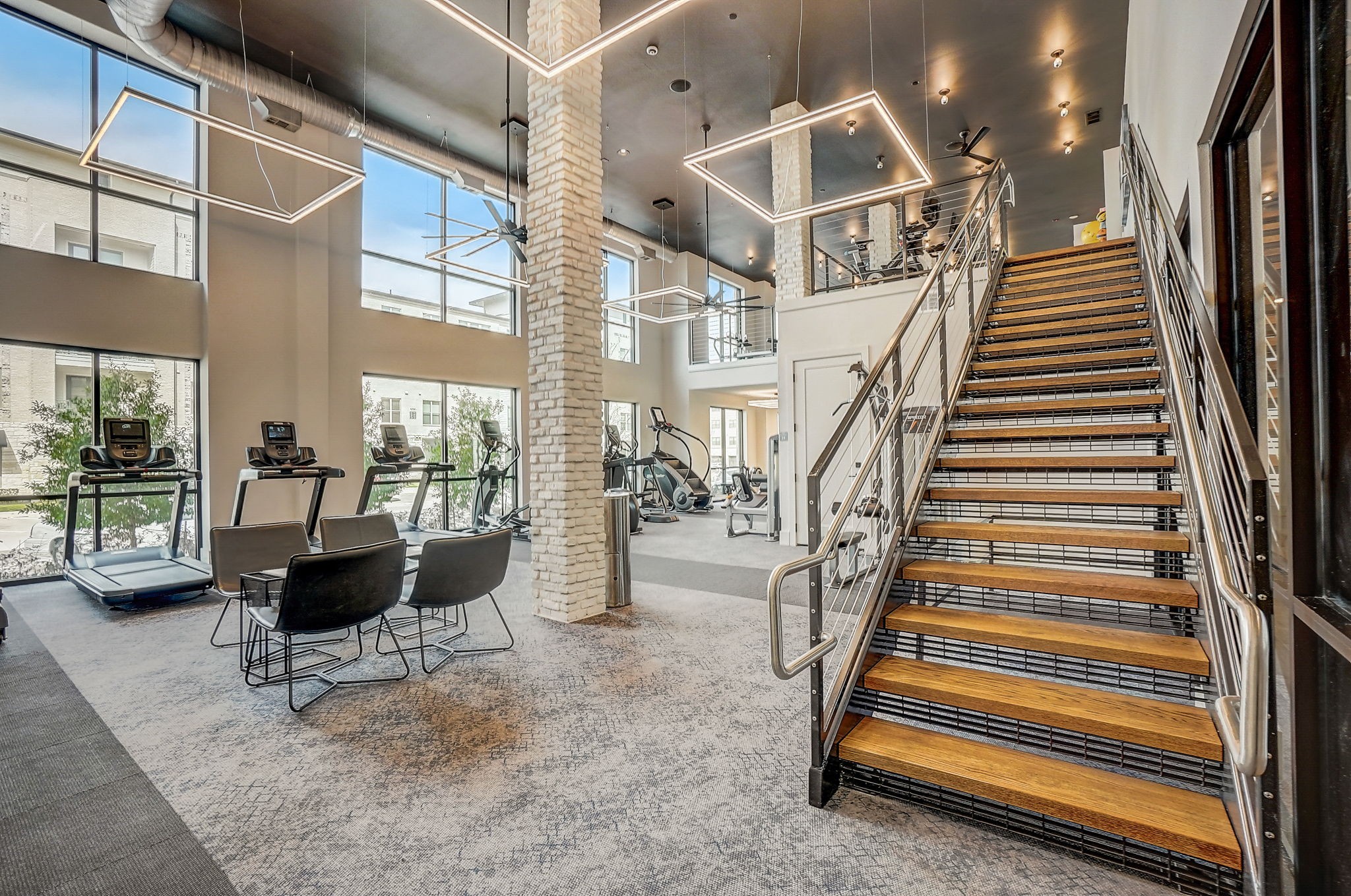the landing of the staircase in the lobby of a building with a gym and chairs