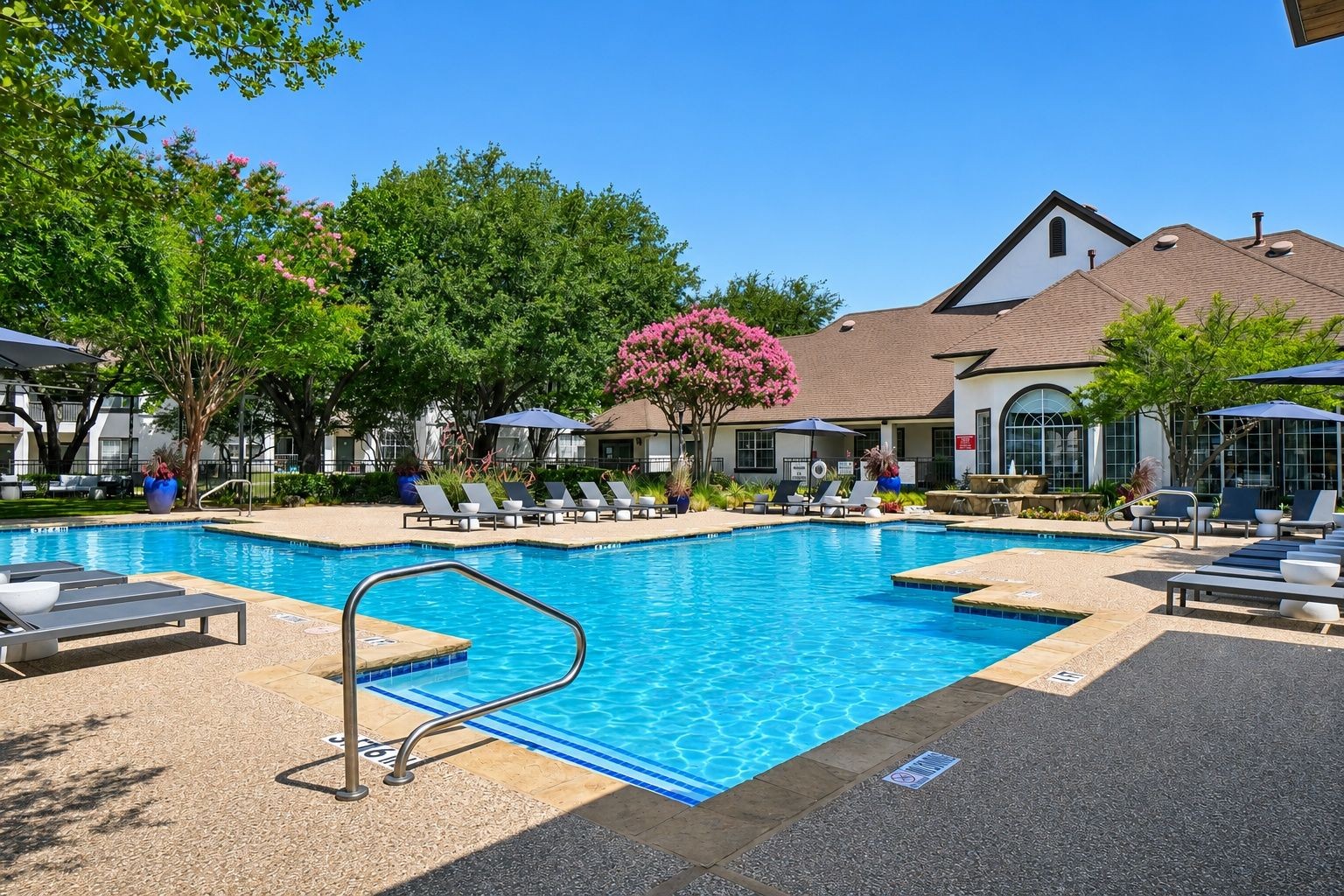 23Hundred at Ridgeview - A tranquil swimming pool area surrounded by trees and lounge chairs under a clear blue sky