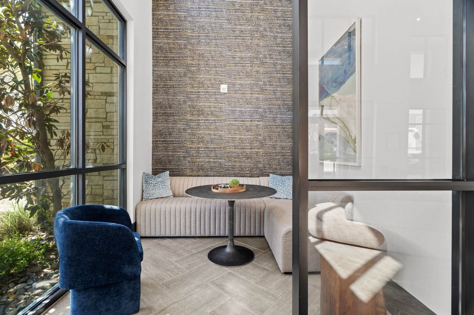 A living room with a blue chair and a round table. at Axis at Watters Creek