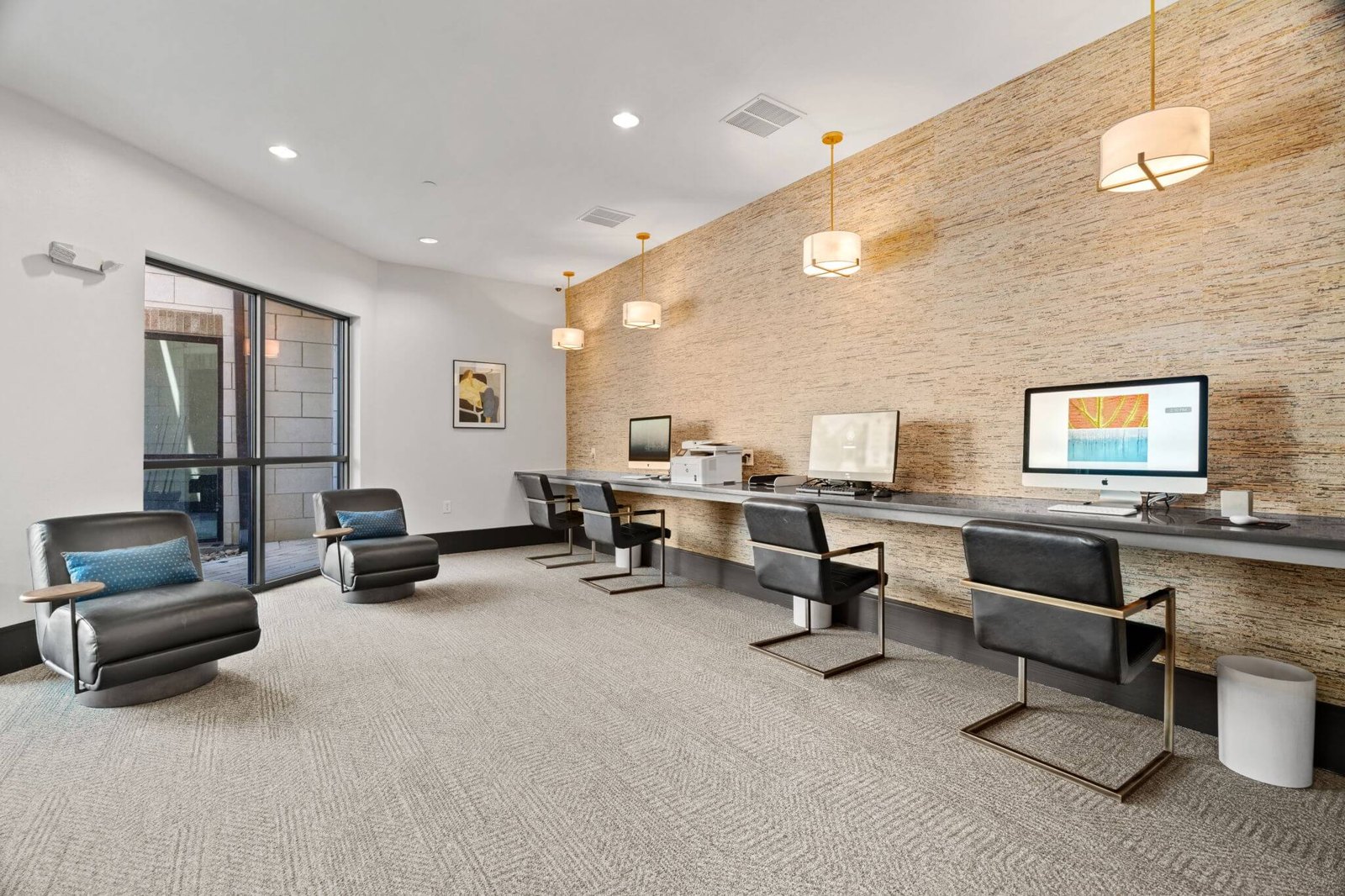 A modern office space with a brick wall and a long desk with chairs. at Axis at Watters Creek