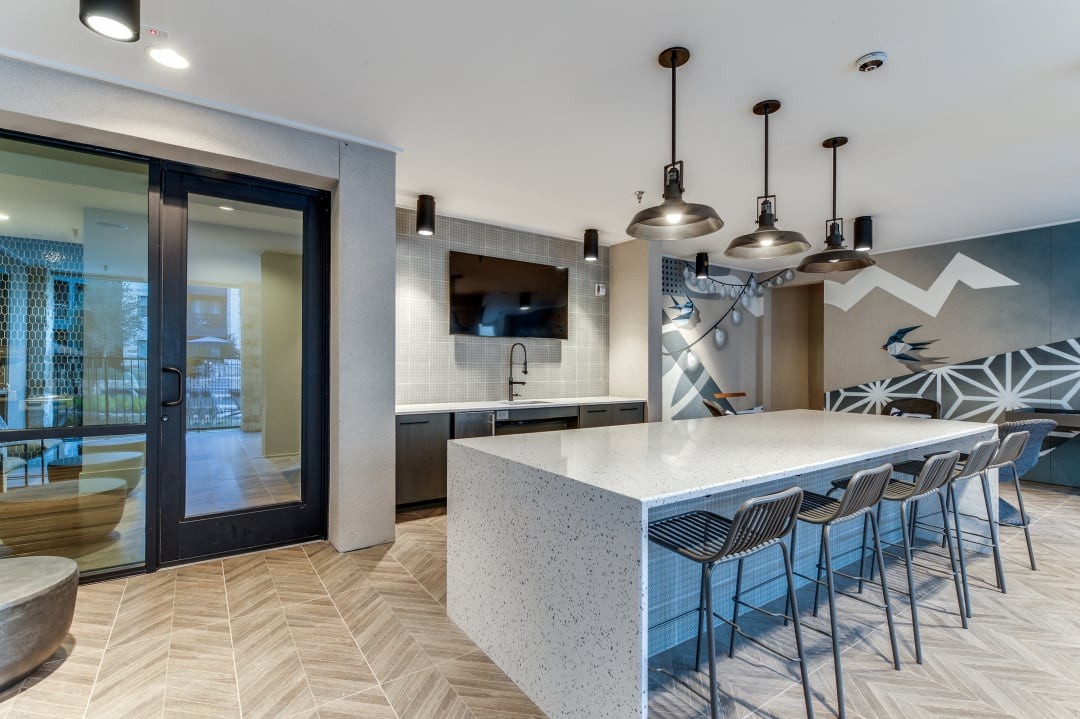 a kitchen with a large white counter top and a long white island with a bunch of chairs
