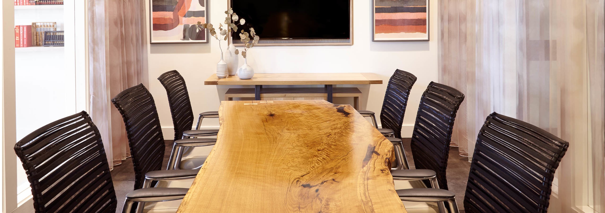 Conference room at AMLI on Riverside with a long wooden desk and black textured chairs with flat screen TV on the wall