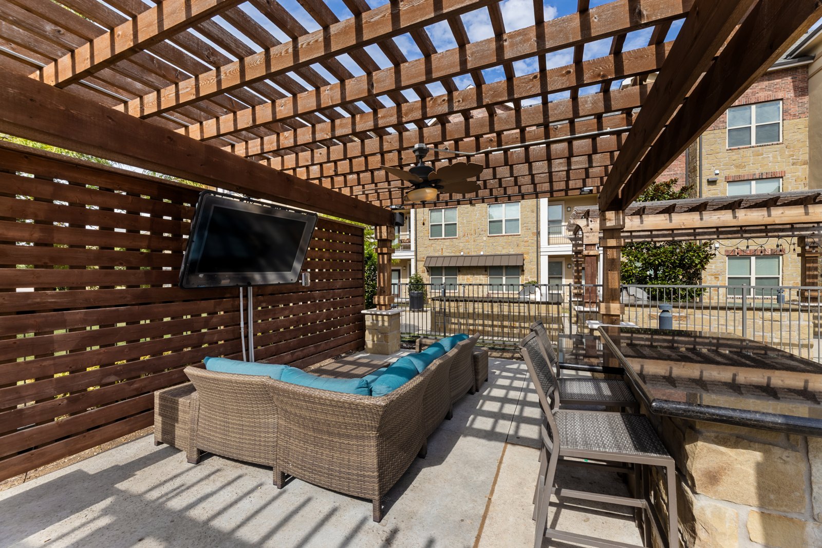 Outdoor lounge patio with seating and television at Auberge of Burleson