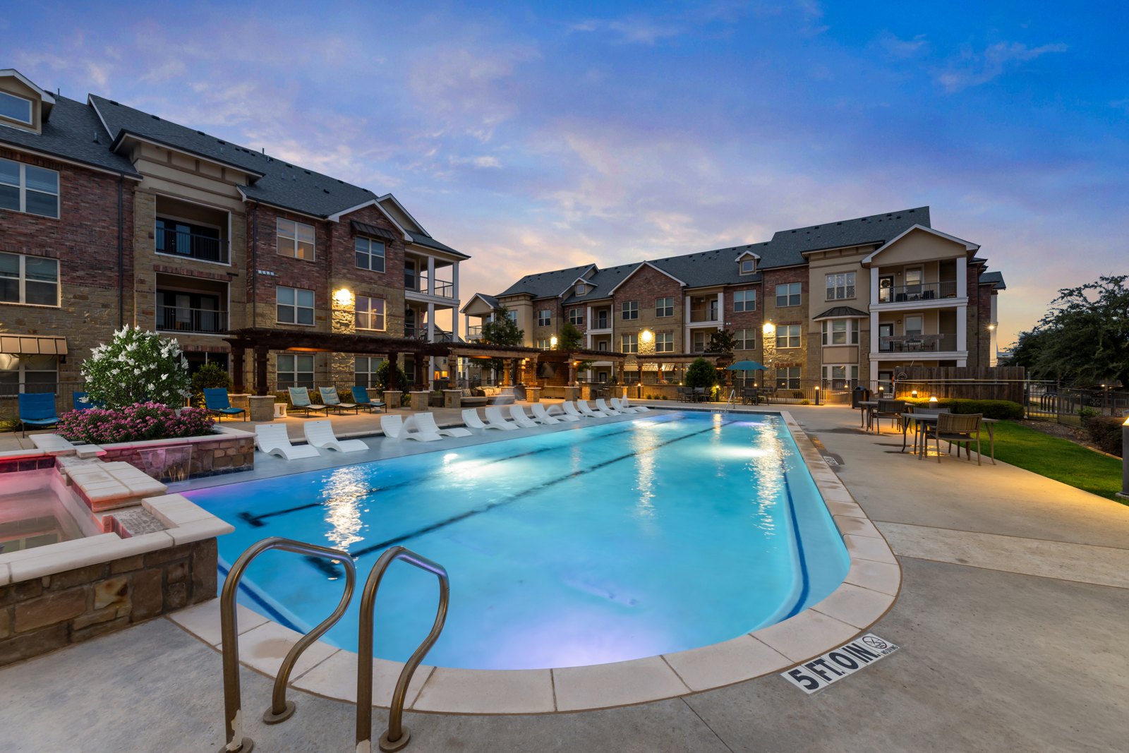 A large swimming pool in front of a building with the name "BROOK" written on the ground. at Auberge of Burleson