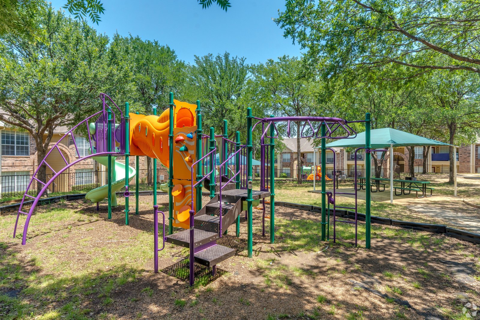 A playground with a purple and orange slide. at Ash Lane Apartment Homes