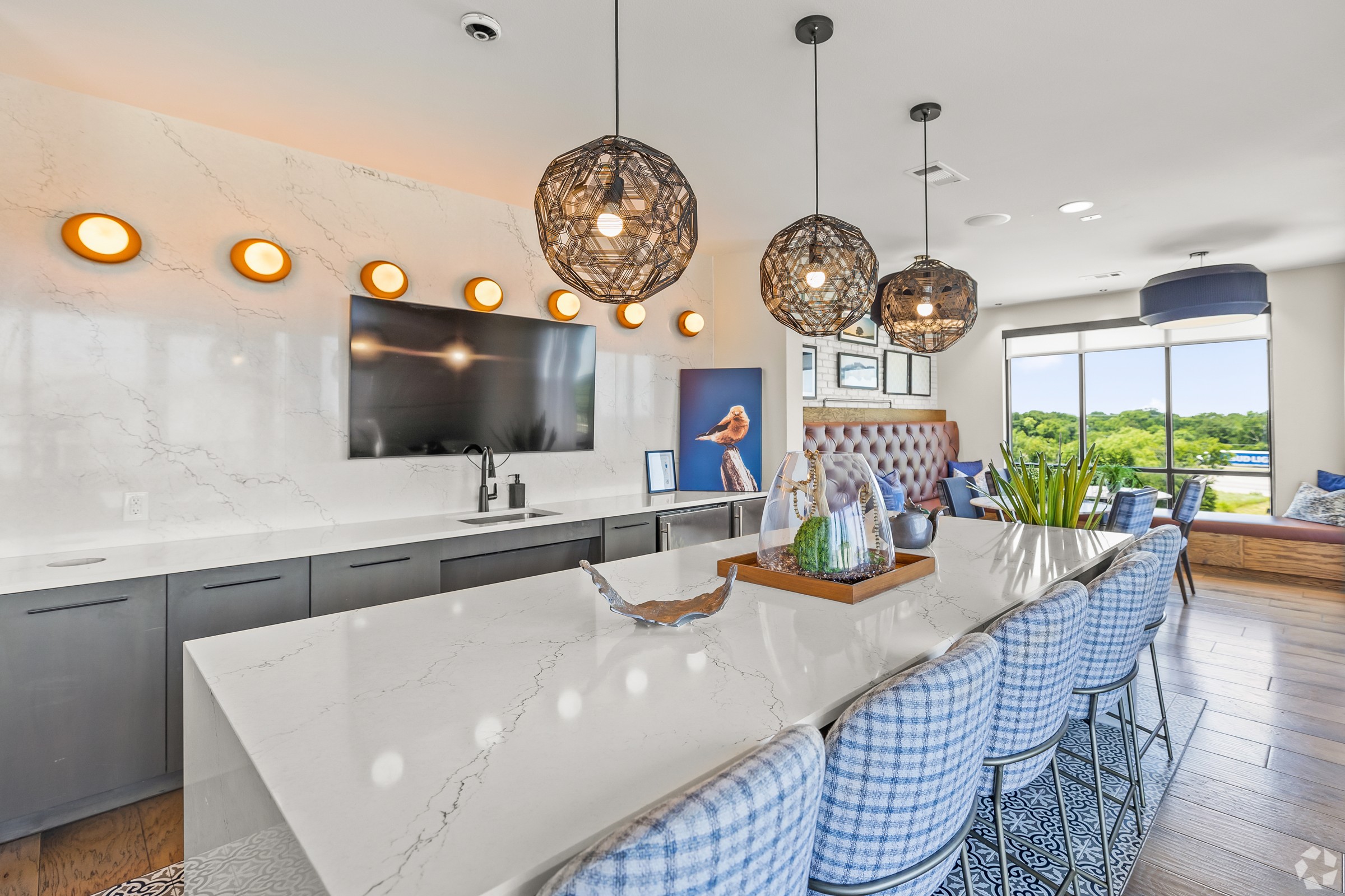 A modern kitchen with a marble countertop and blue chairs