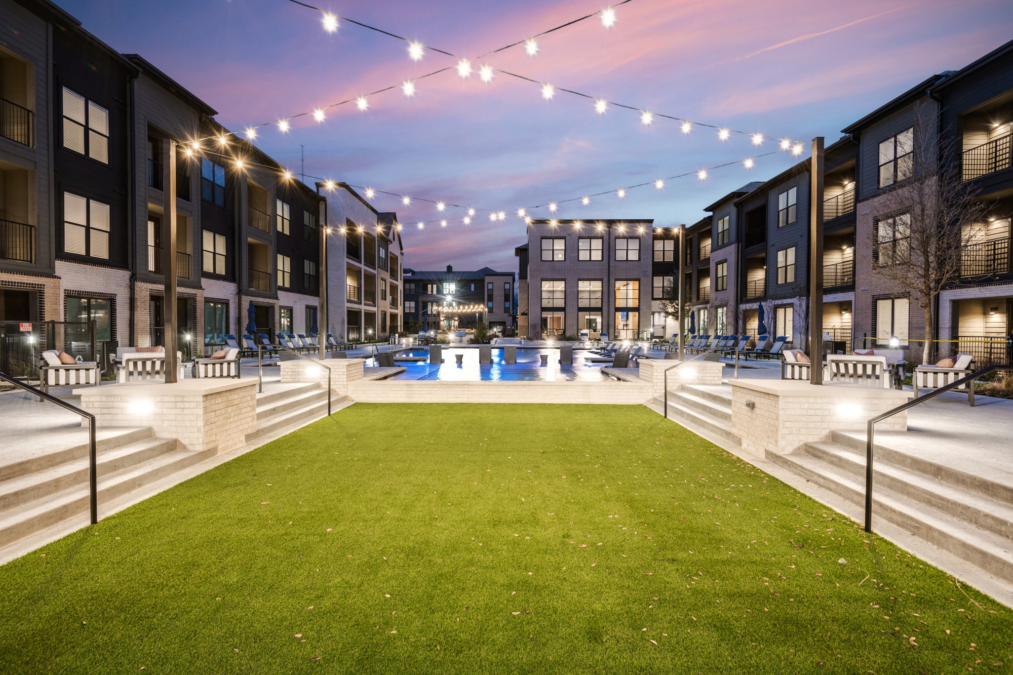 Central courtyard lawn with string lights and pool view