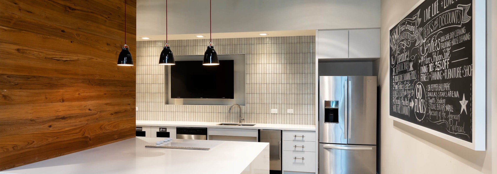 AMLI Frisco Crossing - Interior of resident serving kitchen at AMLI Frisco Crossing apartment building with stainless steel appliances and big screen TV