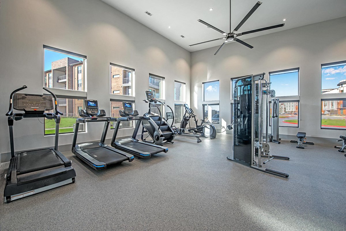 A spacious gym with treadmills, elliptical machines, and a fan. at Axis Grand Crossing
