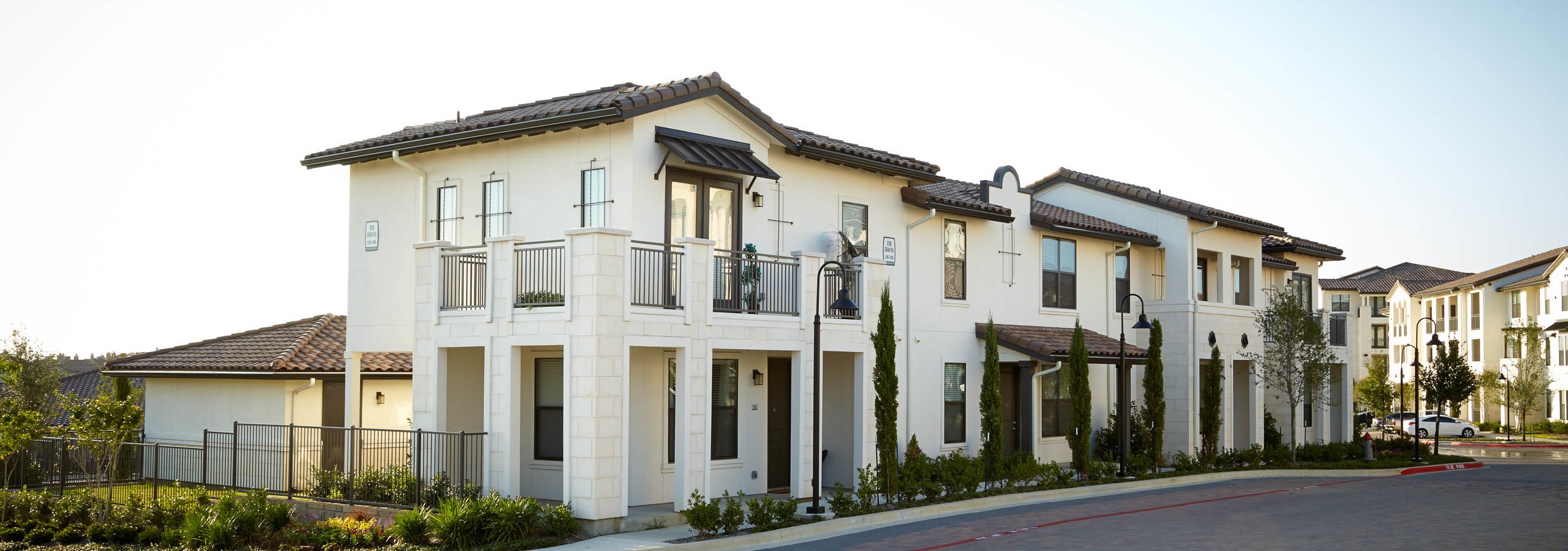 Alternate angle from the side of AMLI on Riverside building with white stucco facade and vibrant surrounding trees and bushes