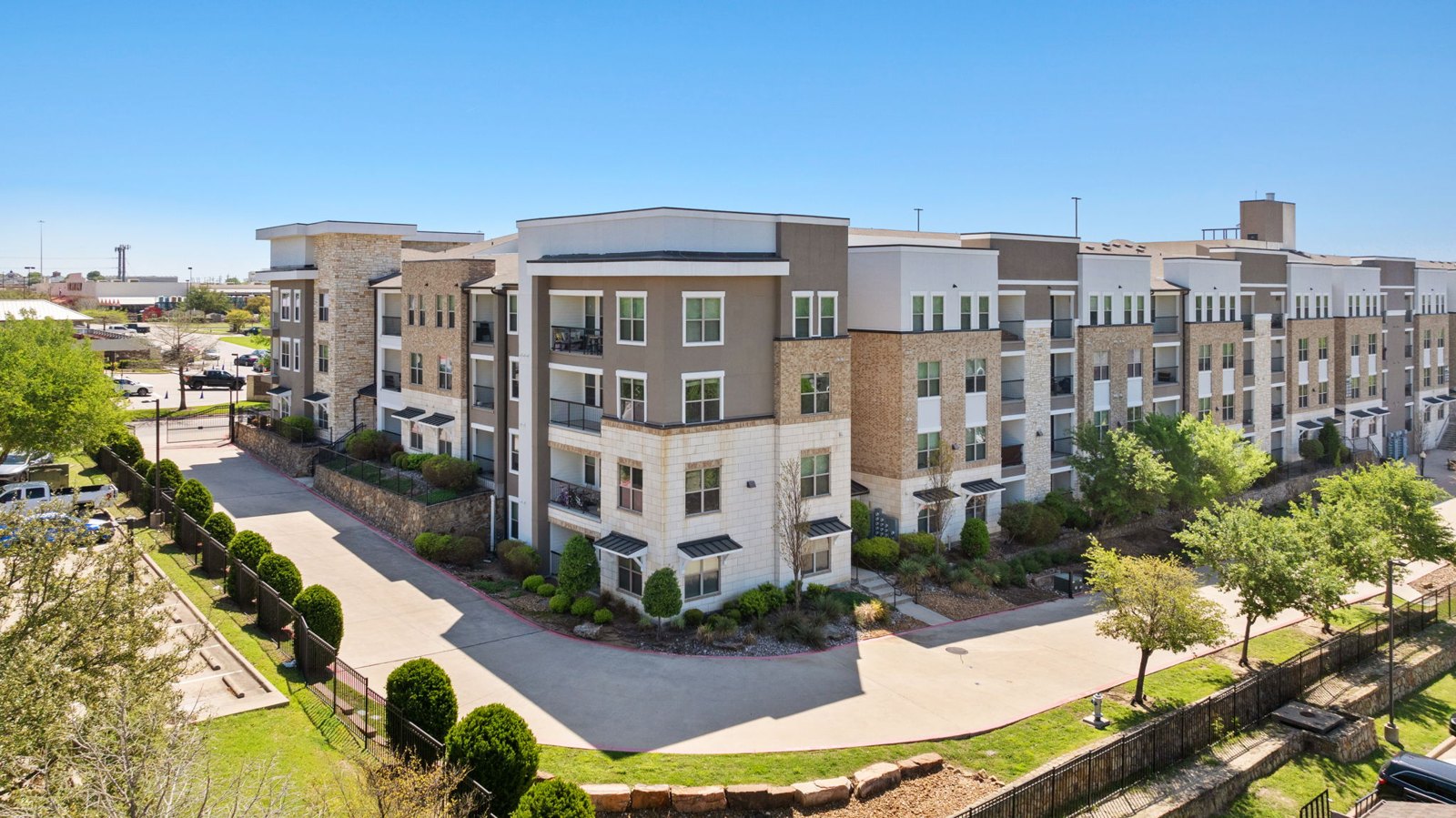 A large apartment complex with a parking lot in front. at Axis at Watters Creek