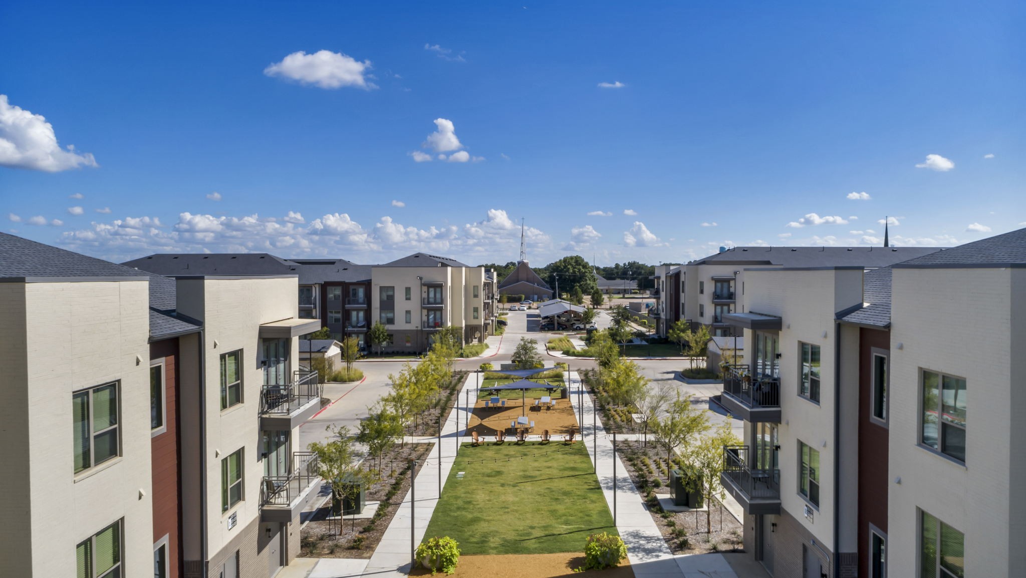 26 at City Point - A view of a courtyard surrounded by buildings with a blue sky and clouds in the background