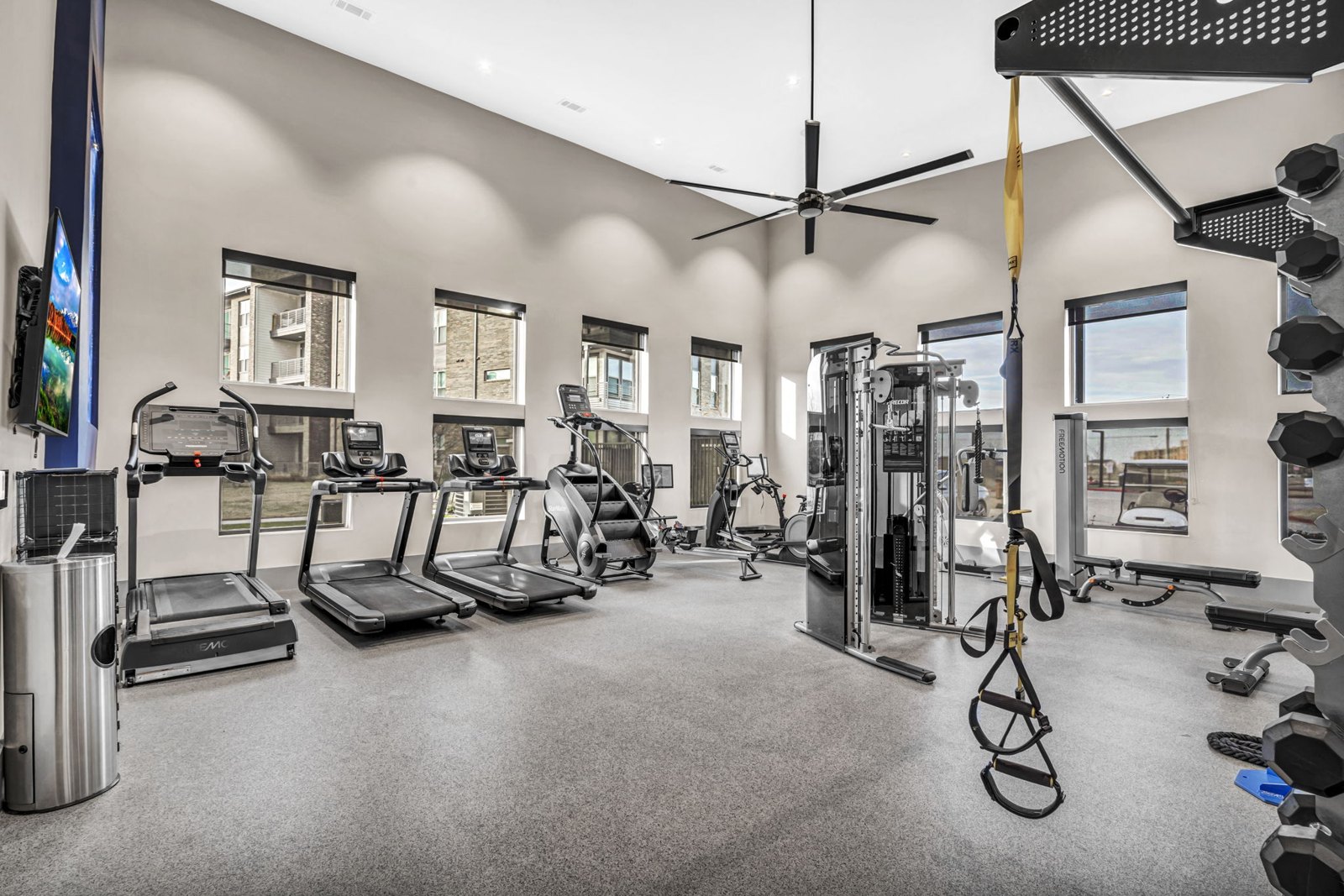 A spacious gym with a variety of equipment including treadmills, weights, and a bench press. at Axis Grand Crossing