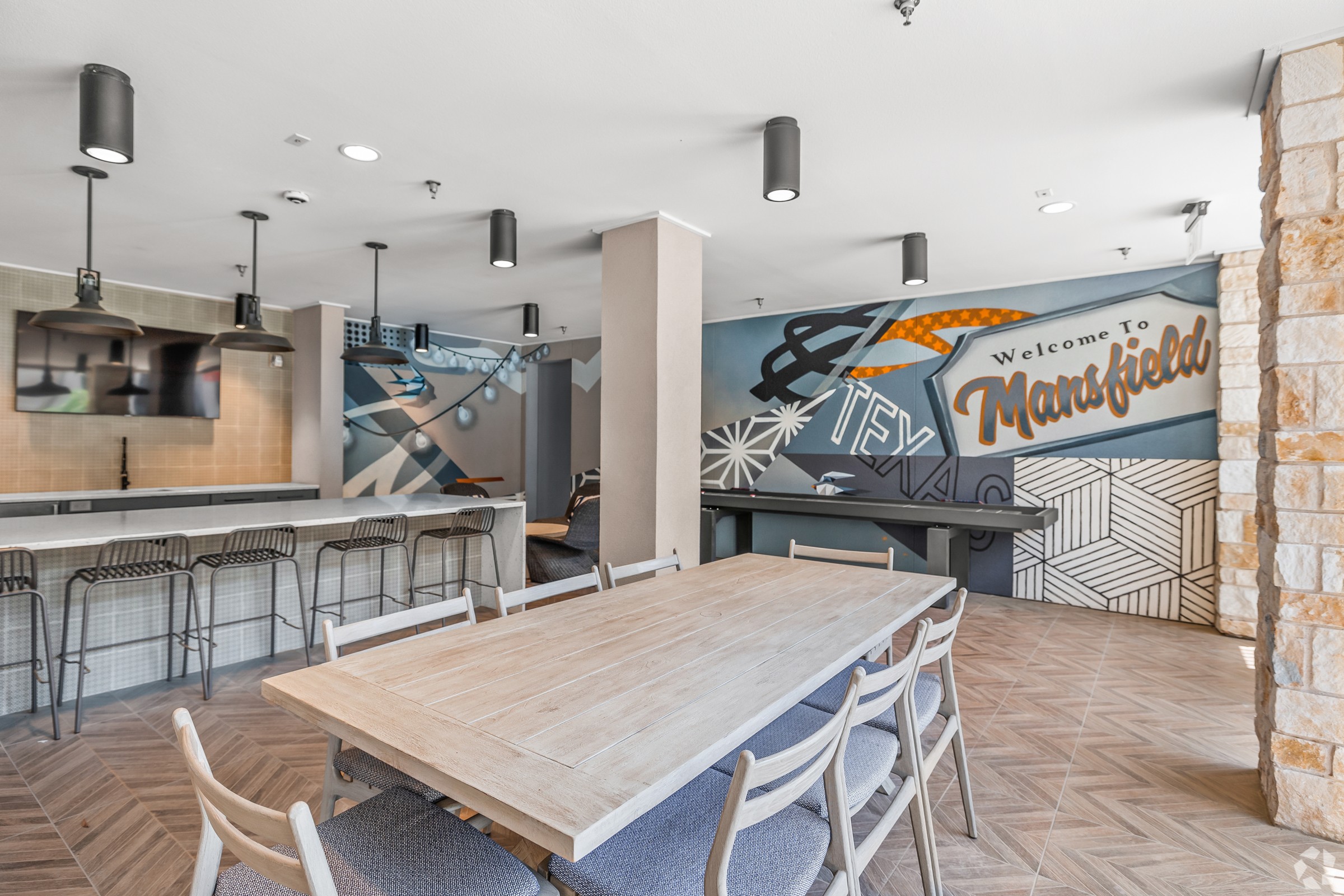 A room with a wooden table and chairs and a mural on the wall