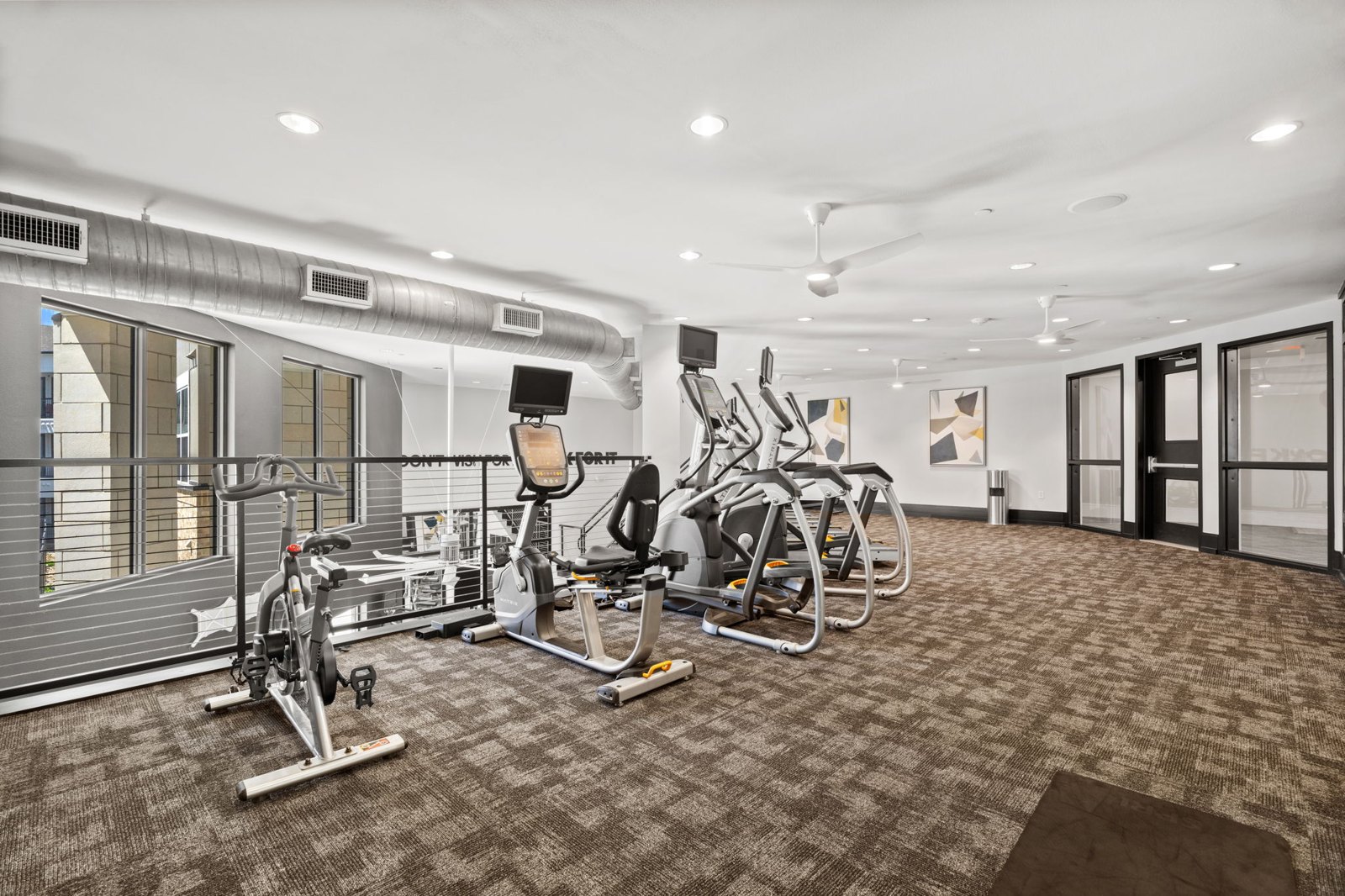A gym with a variety of exercise equipment including treadmills, stationary bikes, and weight machines. at Axis at Watters Creek