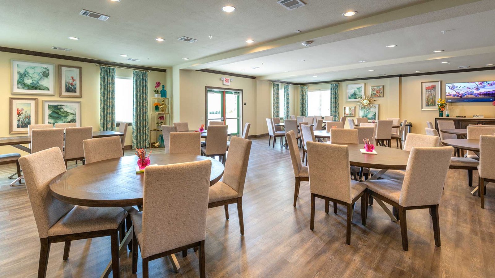 A collection of circular dining tables and chairs in an open room with artwork on the back walls. at Bell Tower Reserve