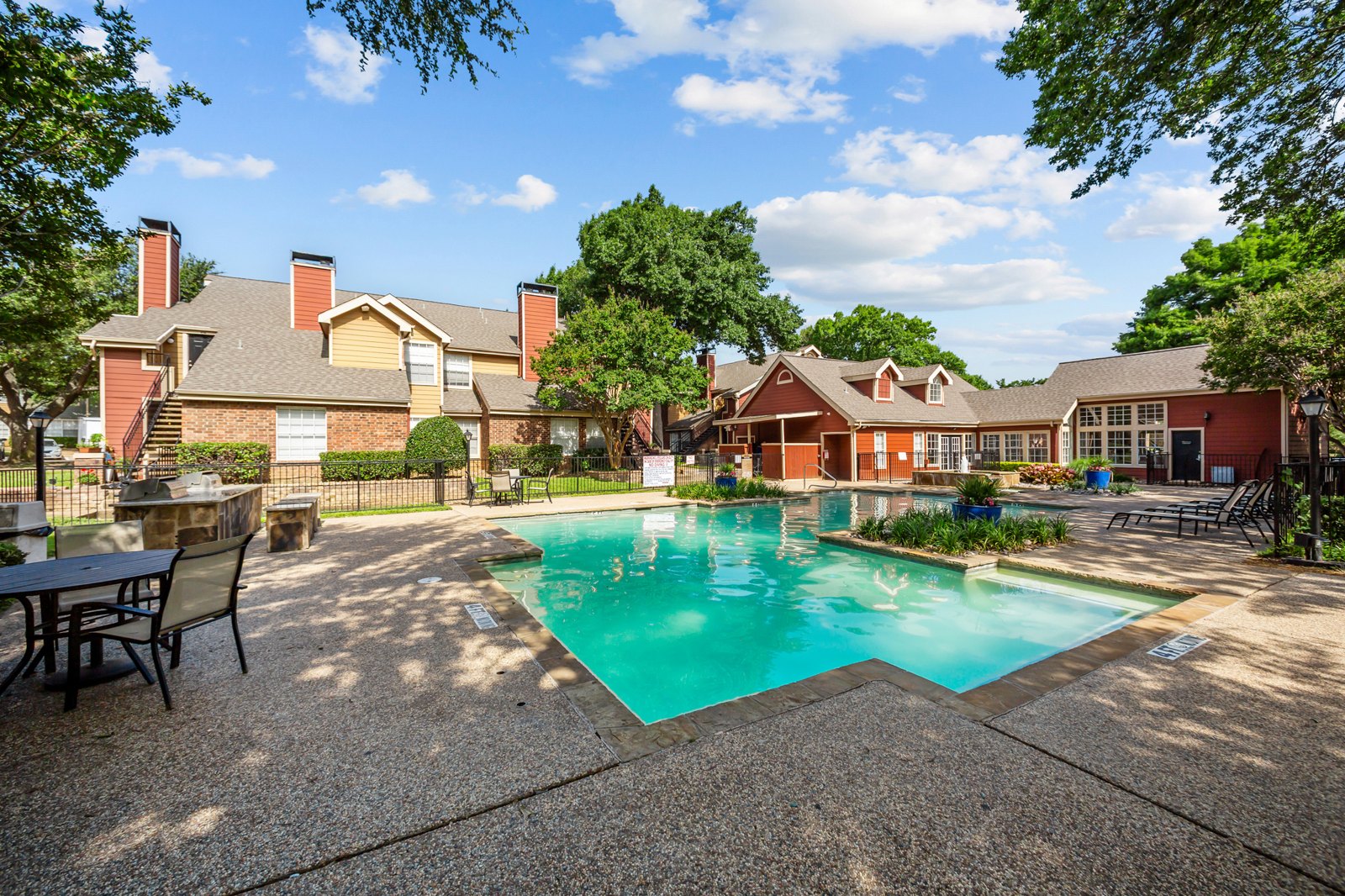 A pool surrounded by a patio and trees. at Bravo Apartment Living