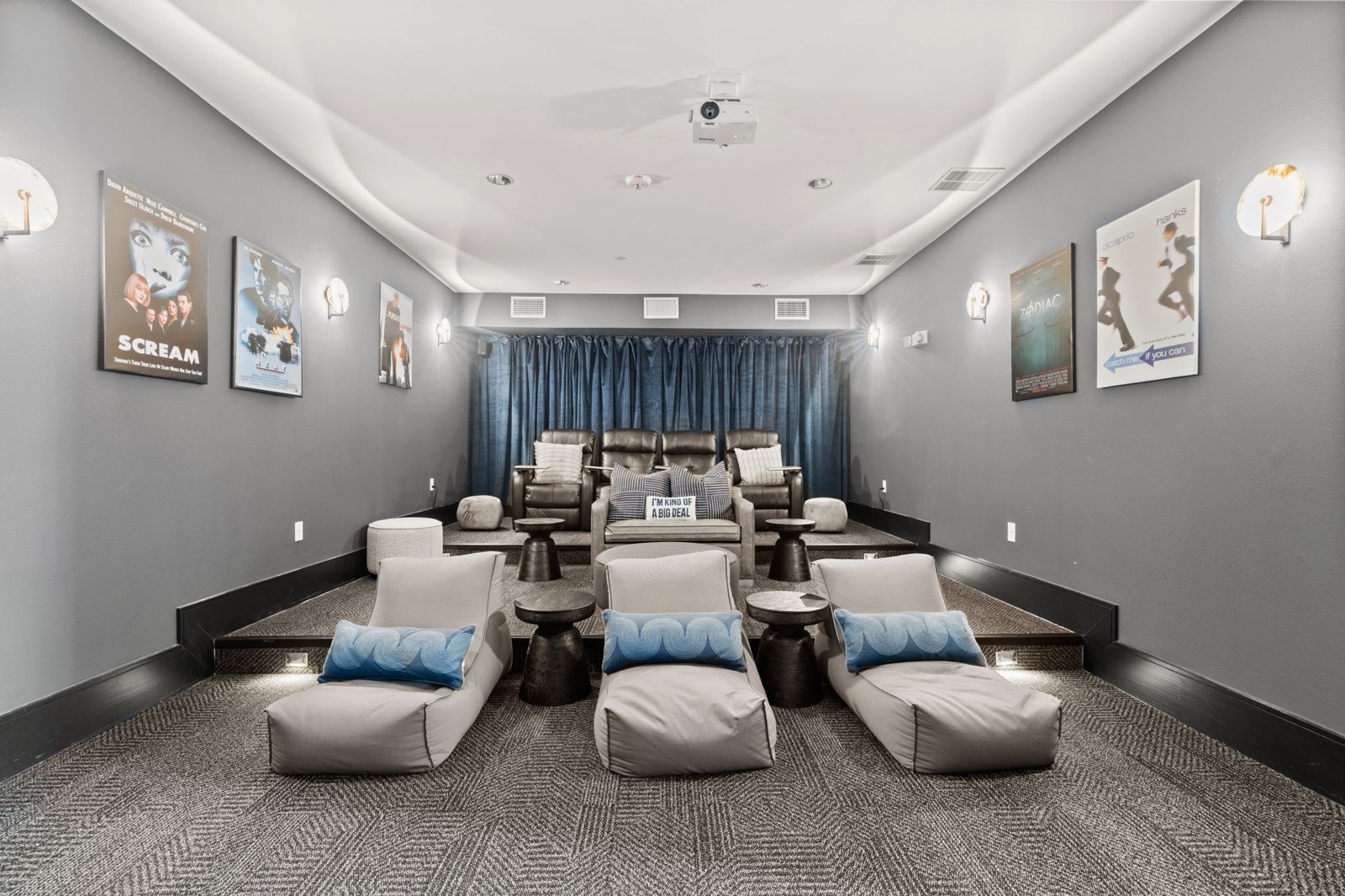 A room with grey walls and a carpeted floor has a row of white chairs with blue pillows. at Axis at Watters Creek