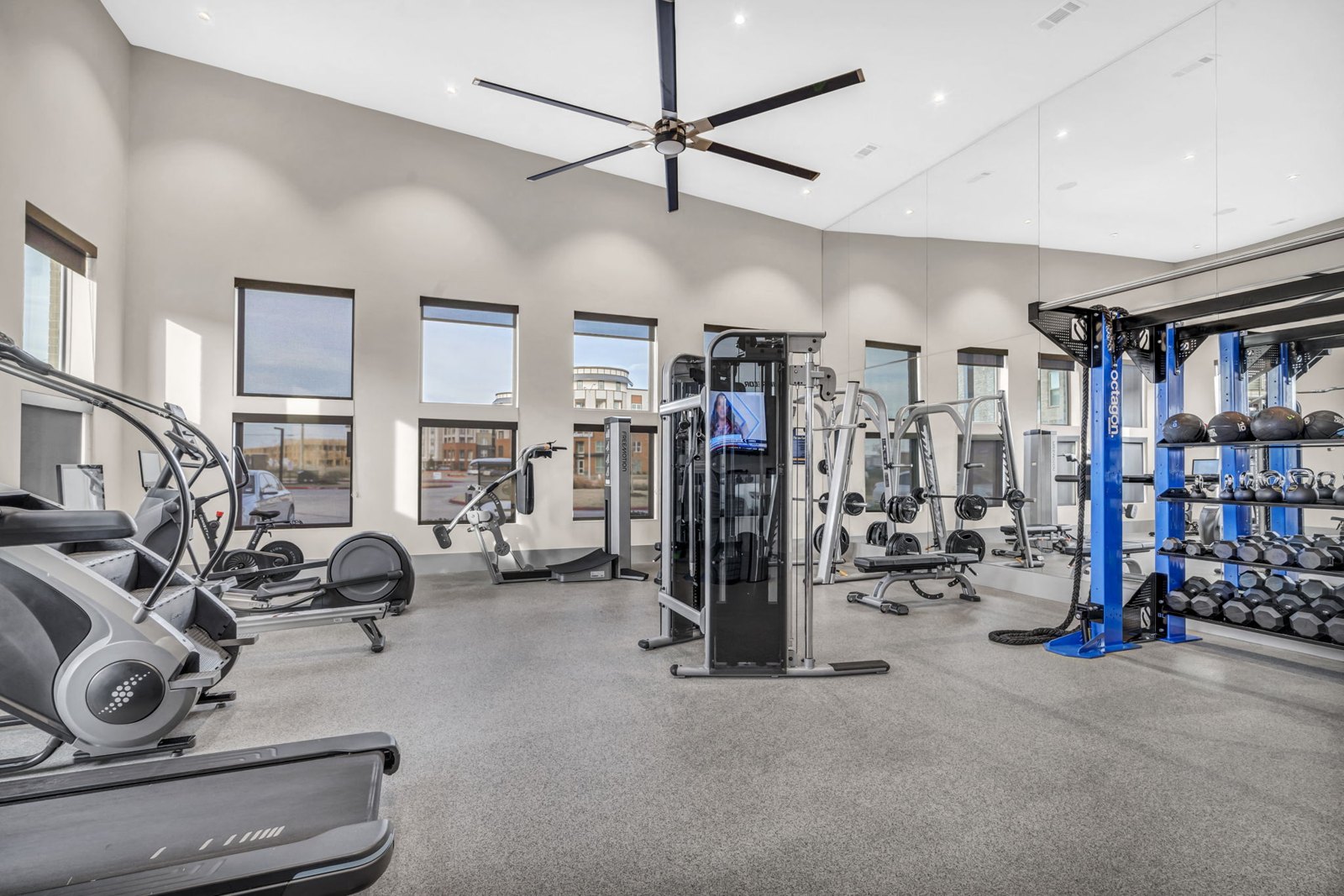A spacious gym with a variety of equipment including treadmills, elliptical machines, and weight racks. at Axis Grand Crossing