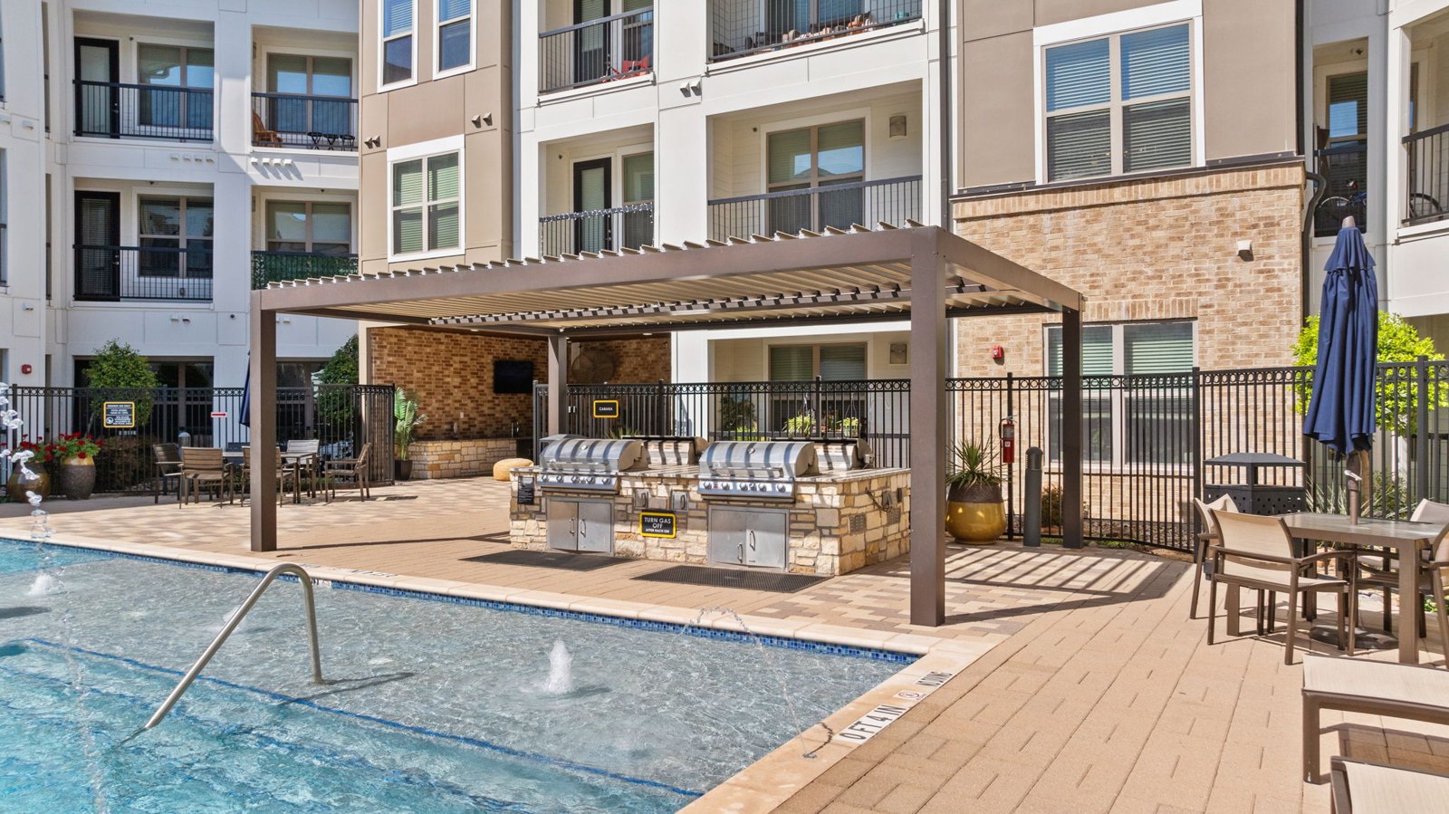 A pool area with a hot tub and a building in the background. at Axis at Watters Creek